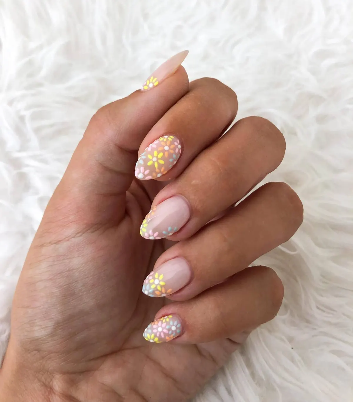 Unhas nude com flores pintadas em tons pastel